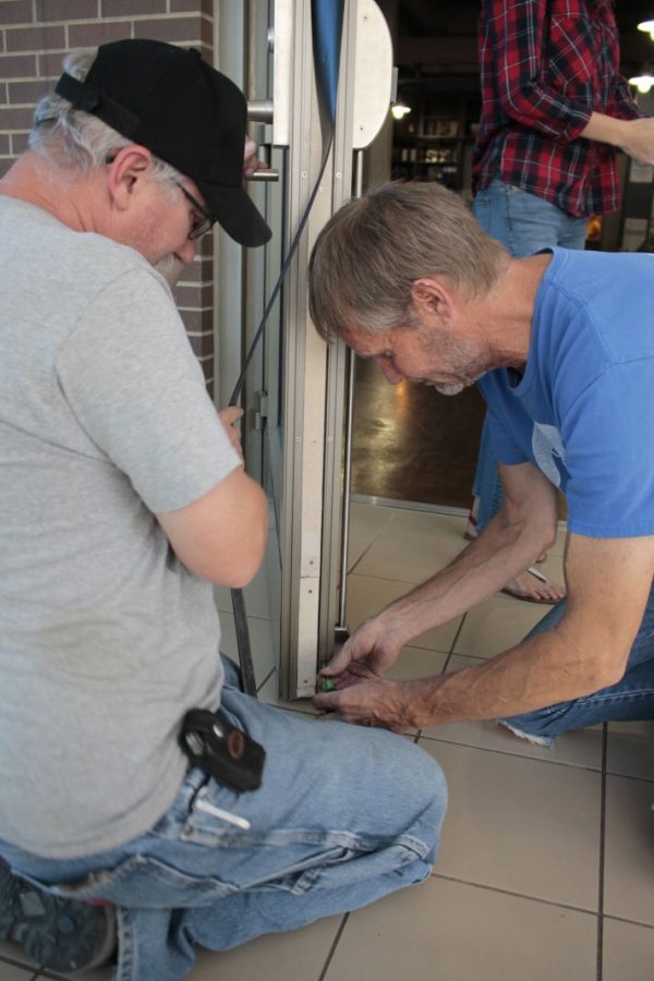 Greg Markus and Ed Baine work together to fix the fire door of the Student Engagement office on Friday, Sept. 23, 2015. Markus said the doors were sagging due to a defective hinge that needed to be replaced. 
