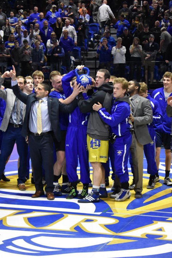 The+Jackrabbit+wrestling+team+celebrates+their+last+home+match+with+a+20-18+win.+The+team+gathers+around+the+Border+Bell.