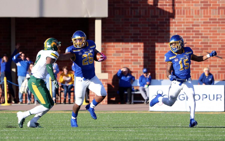 South Dakota State running back Mikey Daniel (26) stiff arms a North Dakota State defender as teammate Cade Johnson looks on Saturday, Oct. 26 at Dana J. Dykhouse Stadium. Despite a strong rushing performance from Daniel and the rest of the backfield, the Jackrabbits fell to the Bison 23-16.