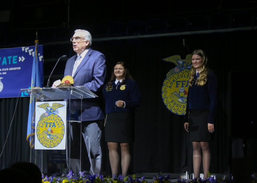 President Barry Dunn addresses State FFA Convention attendees while outgoing State FFA Treasurer Paige Lehrkamp, left, and outgoing State FFA Sentinel Trinity Peterson look on.
