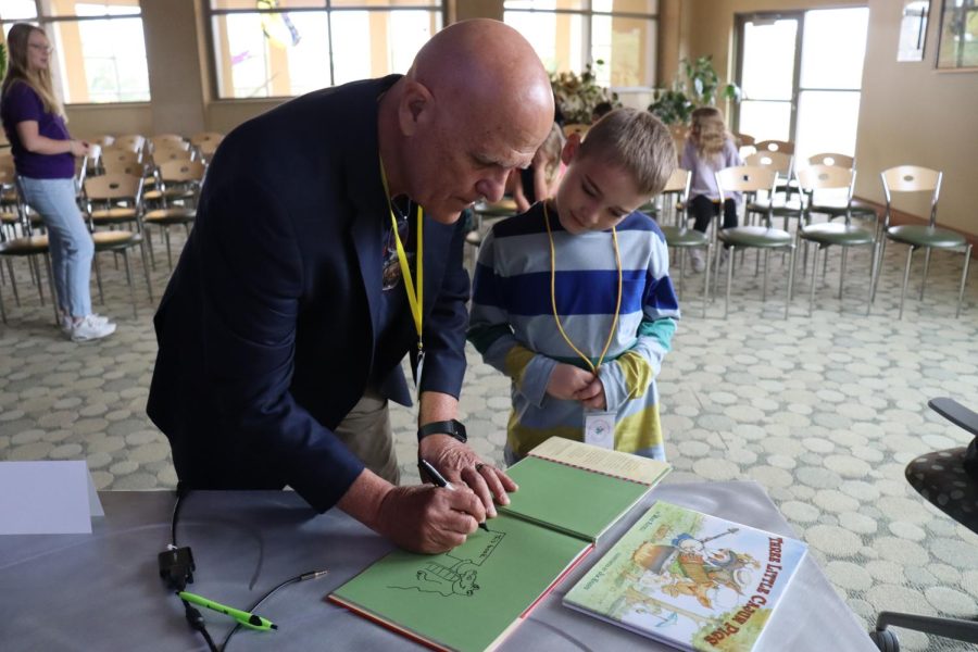 Children’s author Mike Artell signs a copy of his book for Prairie Learning Academy third grader, Weston Clark.